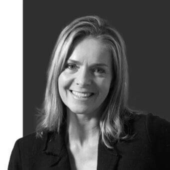 Grayscale portrait of a woman with shoulder-length hair, wearing a dark garment, against a divided dark and white background