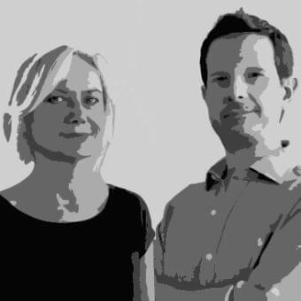 Grayscale portrait of two people facing each other with soft lighting and simplified facial features against a plain background