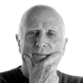 Bald man portrait, Bruno Fattorini, black and white photography, contemplative pose, dark sweater, neutral background, detailed skin texture.