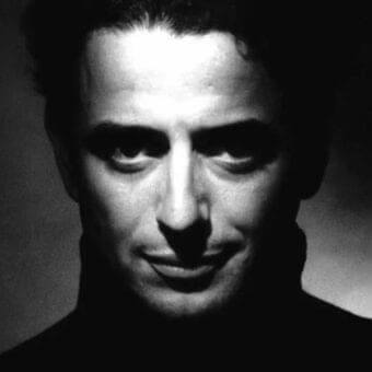 Dark and light contrast on a shadowed male portrait with forward gaze and subtle smile