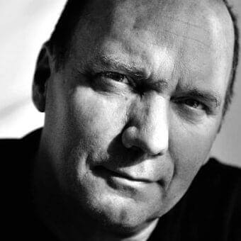 Man’s face in close-up with angled gaze, defined features, stubble and strong light-shadow contrasts