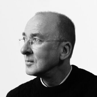 Black and white portrait of Dietmar Joester, a man in profile wearing a dark sweater and white collared shirt, against a light gray background.