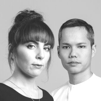 Black and white portrait of Lanzavecchia Wai, featuring a woman in a black top and a man in a white mandarin collar shirt, neutral expressions.