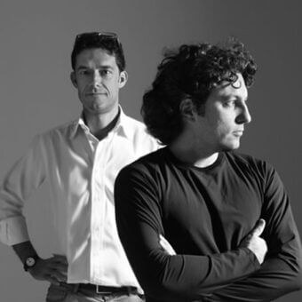 Black and white portrait of two men, gradient gray background, one in black shirt, one in white, names “leonardi marinelli” below.