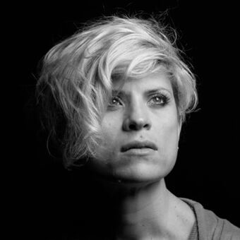 Black and white portrait of Lorella Agnoletto with short, layered hair, fair skin, and direct gaze against a dark background.