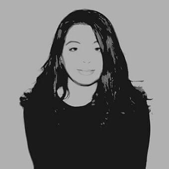 Grayscale portrait depicts a person with long dark hair and a slight smile facing forward against a medium gray background