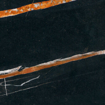 Dark marble texture with diagonal orange-brown and white veins, displaying a speckled grain and hairline fractures across a black surface.