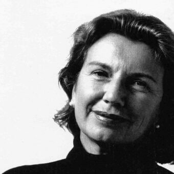 Black and white portrait of Daniela Pappa, a woman with short dark hair, wearing a dark turtleneck, against a light gray backdrop.
