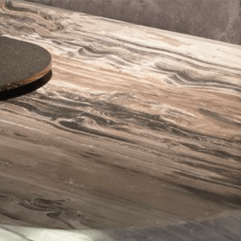 Resin tabletop with swirling brown and cream wood grain pattern, featuring a dark gray circular coaster on the polished surface.