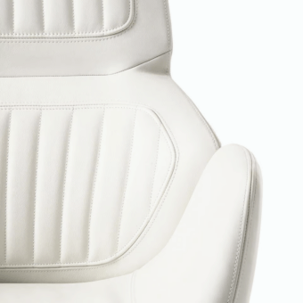 Superior Giorgetti Calathea Bergere chair in white synthetic leather with segmented vertical stitched padding and curved lines