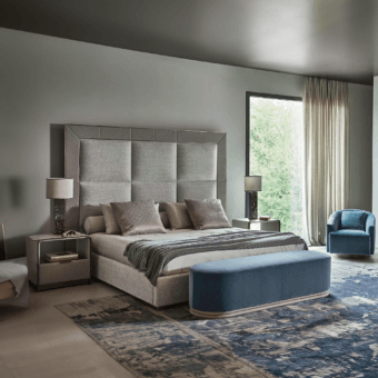 Superior Rugiano Aura bed with light textile upholstery, a padded headboard framed by an embroidered border, built in Italy