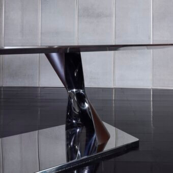 Superior Rugiano Rea table with a dark glossy ebony top and twisting bronzed brass base built on a reflective metal platform