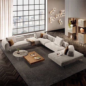 Living room with light gray modular sofa, wood coffee table, dark rug, and cityscape view through grid window; neutral gray walls with beige wall sculptures.
