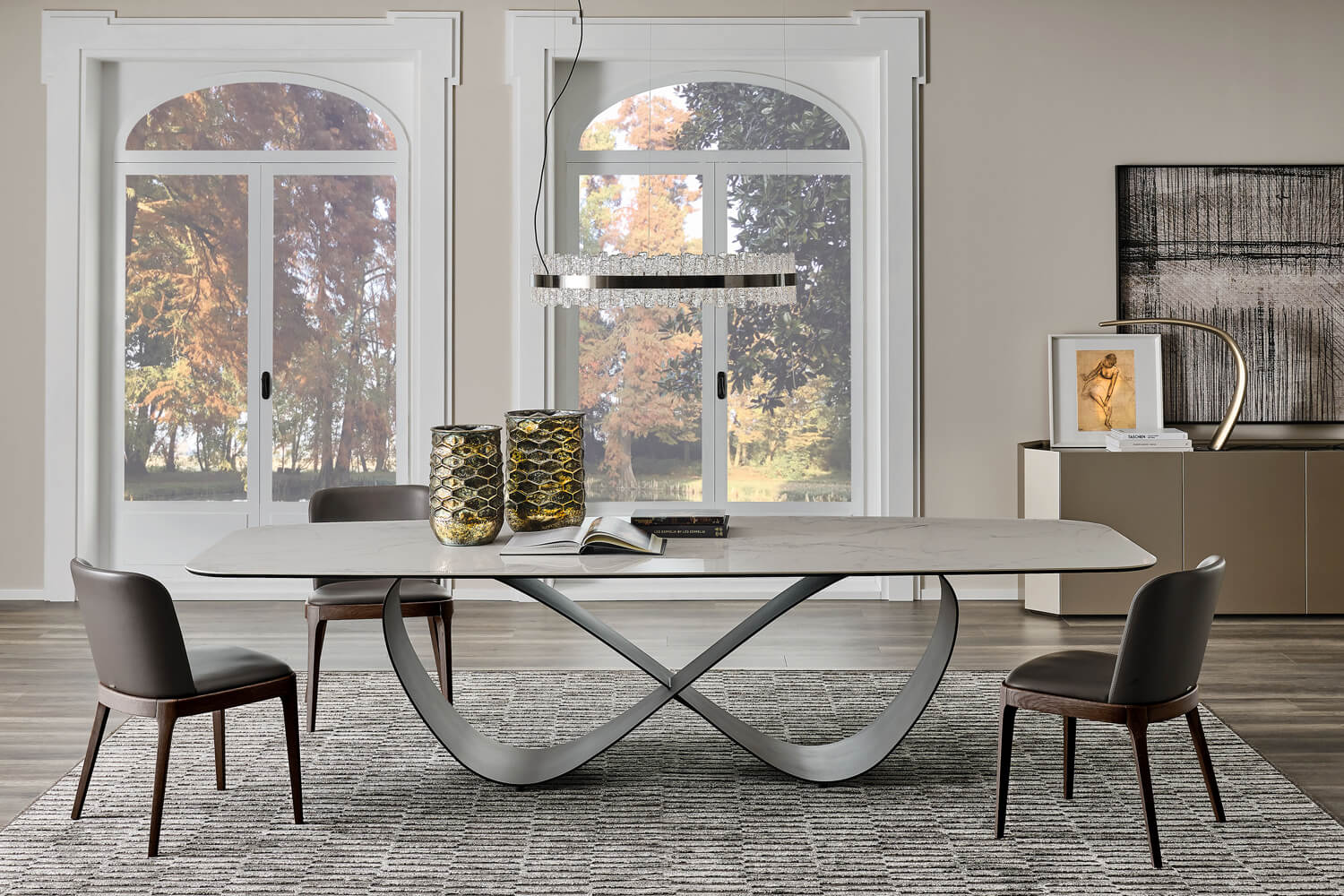 Cattelan Italia Keramik table, white marble top, dark gray butterfly base, with gray and brown dining chairs, gold vases, and linear chandelier.