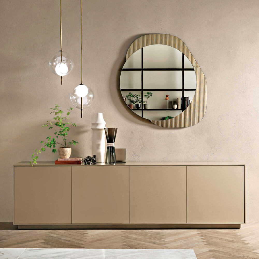 Rectangular sideboard with six doors, gold framed round mirror, and two spherical pendant lights in a minimalist interior setting.