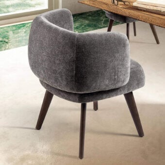 Zeppelin chair, gray fabric upholstery, rounded high-back design with tapered dark wood legs in a studio setting.