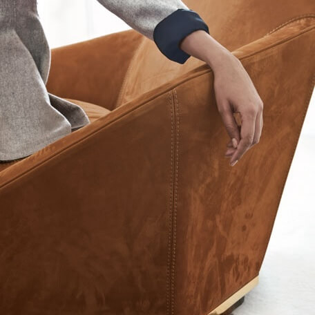 Longhi Aoyama lounge chair, rust-orange velvet, squared back with vertical seam, wide armrests, gold-toned base, studio lighting.