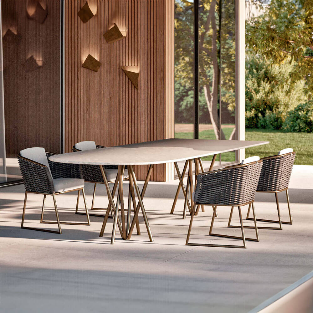 Marble dining table with brass legs and six woven black chairs on a gray tiled patio, modern outdoor setting.