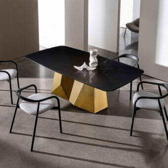 Extendable dining table, dark gray matte finish, geometric light wood base, with four black metal chairs and ceramic decor.