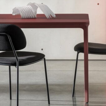 Sovet Italia slim 20 table, burgundy glossy surface, black metal legs, paired with curved black chairs, white feather sculpture displayed.