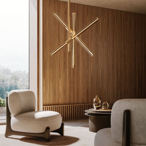 Brass chandelier with six arms hangs above walnut wood paneling, beige armchairs, and a dark brown rounded rectangular coffee table.