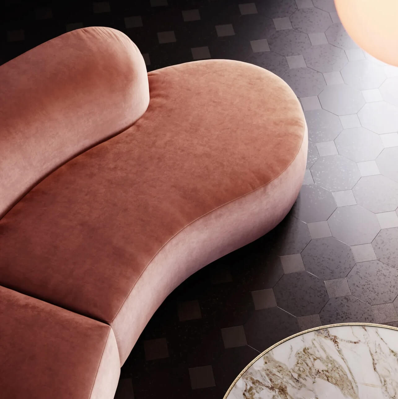 Terracotta velvet sofa with rounded cushions, gray geometric tile floor, and circular marble top table in a contemporary setting.