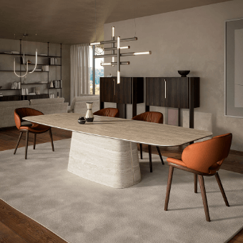 Dining table with light beige marble top and textured base, surrounded by burnt orange and dark gray chairs, walnut sideboard, rug, chandelier.