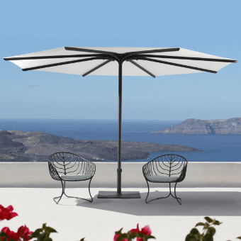 Cantilever umbrella with gray canopy and dark gray metal ribs stands on white terrace with chairs, overlooking coastal landscape and blue sea.
