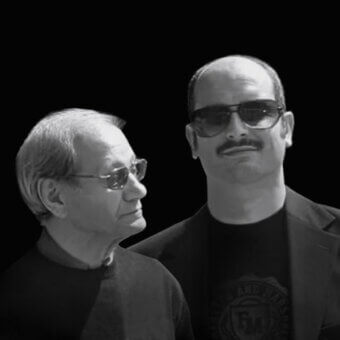 Black and white portrait of two men in profile, wearing sunglasses and dark shirts, against a black backdrop, minimalist composition.