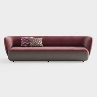 Burgundy velvet swan sofa with taupe leather trim, rounded cocoon shape, black cylindrical legs, and geometric patterned throw pillow.