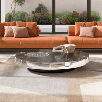 Willy coffee table, dark marble top, circular cutout, chrome band, rotating base, modern interior, orange sofa, natural light.
