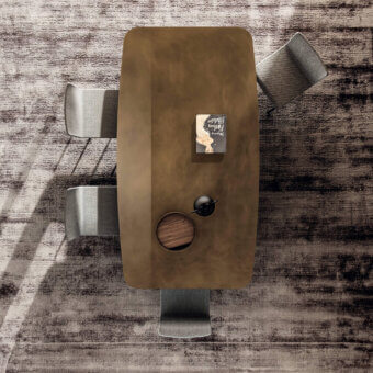 Lago Janeiro table, wood tabletop, irregular shape, gray chairs, inlaid stone, button details, textured light gray floor, studio lighting.