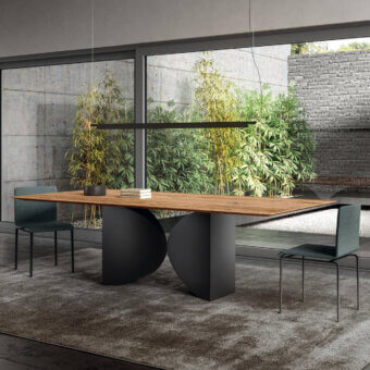 Lago meet table, wood tabletop, black bases, with green chairs, black pendant, glass wall, gray rug, modern interior setting.