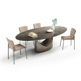 Elliptical table with dark gray matte top and sculptural gray base, surrounded by six light beige fabric chairs in a studio setting.