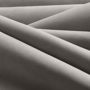 Light gray layered material texture with subtle grain, matte finish, and intersecting angular forms creating shadows and depth.