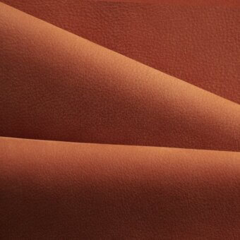 Folded nk rust textile with a pebbled texture, displaying three overlapping layers and subtle tonal variations under diffused lighting.