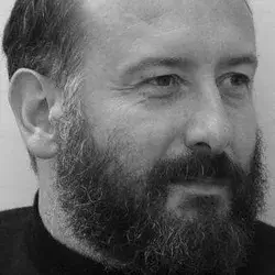 Black and white portrait of Paolo De Lucchi, a man with a beard and receding hairline, wearing a dark turtleneck sweater.