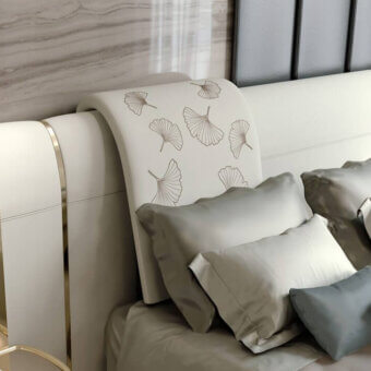 Wave bed, beige fabric, curved headboard with gold metal accents, gray and blue pillows, marble and ribbed wall paneling.
