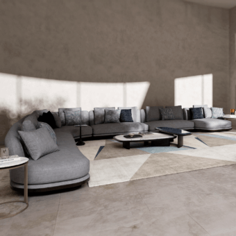 Gray fabric sectional sofa with rounded shape and plush cushions, paired with dark metal side and coffee tables on a geometric rug.