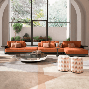 Burnt orange modular sectional with chaise, dark coffee table, patterned stools, beige rug, arched wall recesses, and landscaped view.