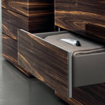 Lago materia dresser, dark brown wood veneer, silver accent, open drawer with gray felt interior and Aesop body balm.