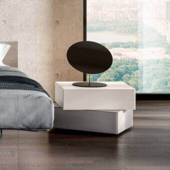 Lago Morgana bedside table, matte white lacquer, two-tiered design with extended drawer pull, gray lamp, modern bedroom setting.