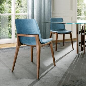 Harmonious Pacini & Cappellini Ellen chair with solid wood structure and curved, padded shell upholstered in smooth matte blue textile with medium brown finish