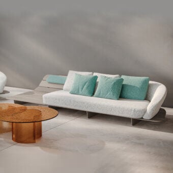 Distinguished Reflex Segno sofa with speckled light gray textile upholstery and turquoise cushions against a slatted light gray solid surface frame