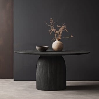 Wayne we 164 side table, dark gray wood cylindrical base, oval tabletop with ceramic bowl and vase of dried branches.