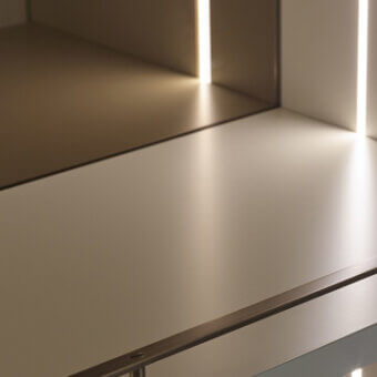 Tree cabinet, light beige finish, minimalist design with horizontal dark gray metal accent and vertical integrated LED lighting.