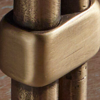Cast brass hardware with bronzed patina, octagonal connector featuring cylindrical rods and textured surface, aged metal finish.