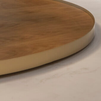 Oak circular table with brass edge, featuring warm brown wood grain and a smooth, rounded tabletop on a white surface.