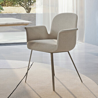 Turri Soul armchair, beige fabric upholstery, curved back with brushed bronze tapered metal legs in a modern interior.