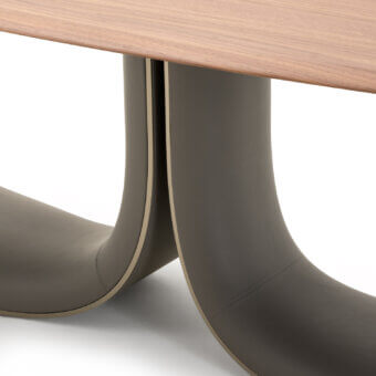 Distinguished Turri Soul table exhibits a serpentine base clad in dark taupe leather with a smooth, light-toned wooden top